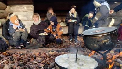 Familiespejder familier sidder foran shelter, der er gryde og æbleskivepande på bålet